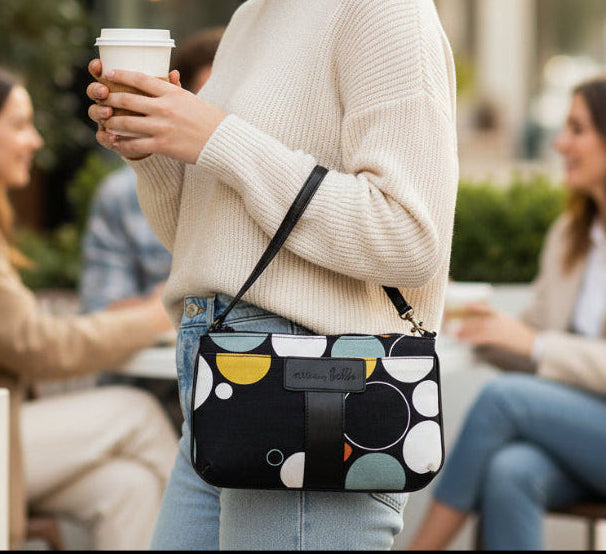 Woman holding a coffee cup and a patterned handbag in an outdoor setting
