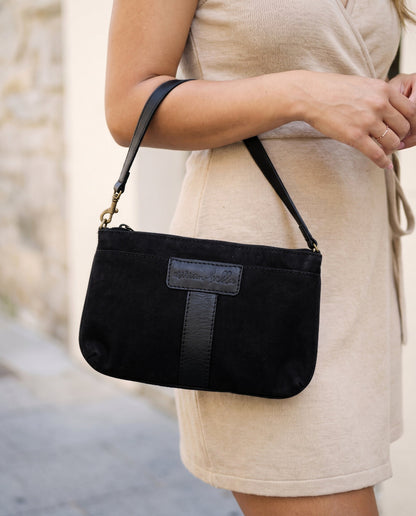 A woman holding the Black Mini Bag outside in a minimalist setting.