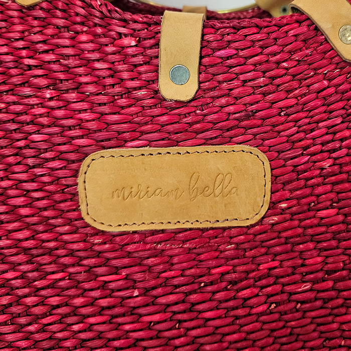 Red woven tote bag with a tan leather accents featuring 'miriam bella' branding.
