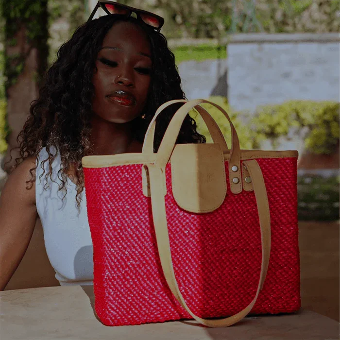 Woman holding a red woven tote bag with beige accents outdoors