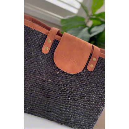 Woven tote bag with leather strap and visible brand name on a neutral background