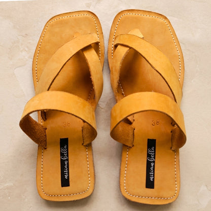 Image of handmade tan leather sandals with cross strap produced by Australian brand Miriam Bella on a light beige background