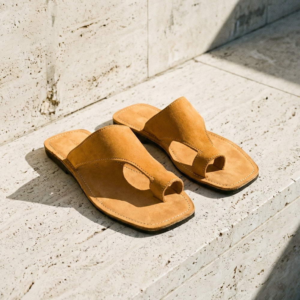 Pair of tan thong sandals on a light stone floor