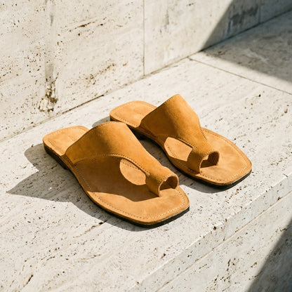 Pair of tan thong sandals on a light stone floor