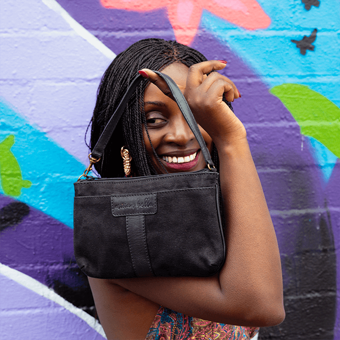 Woman holding a black handbag against a colorful graffiti wall