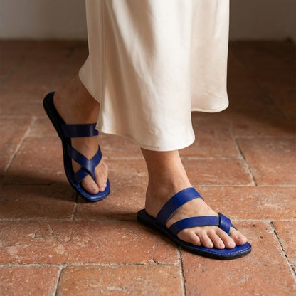 Person wearing handmade indigo leather sandals with cross strap produced by Australian brand Miriam Bella on a tiled floor