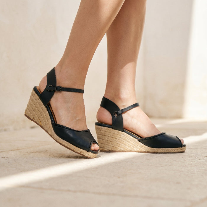 Person wearing black wedge sandals on a concrete