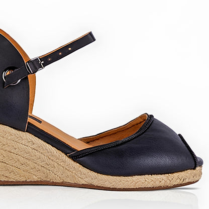 
Close up of a handcrafted leather black wedge espadrille sandals with jute sole by Miriam Bella on a white background.