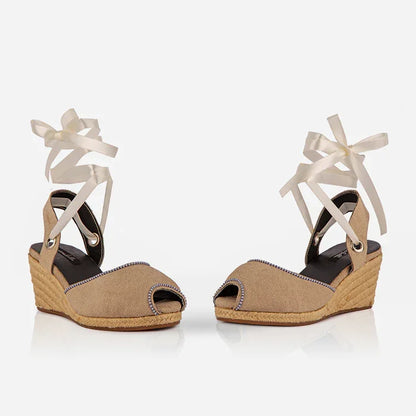 Gaia cream canvas closed toe espadrille wedge heels shown at an angle with white ribbon ankle ties.