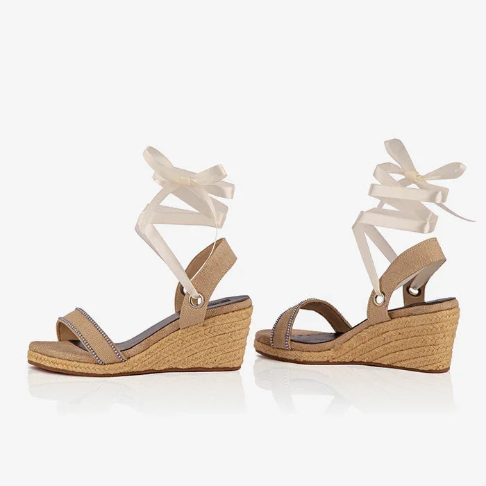 Pair of Gaia cream canvas wedge espadrilles shown from the side with white ribbon ankle ties.