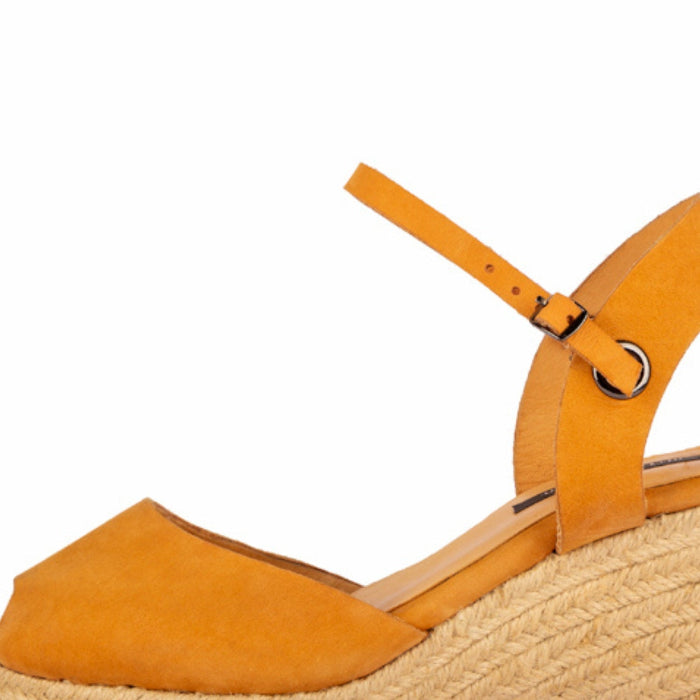 A close up of a handcrafted leather ochre wedge espadrille sandal with jute sole by Miriam Bella on a white background.