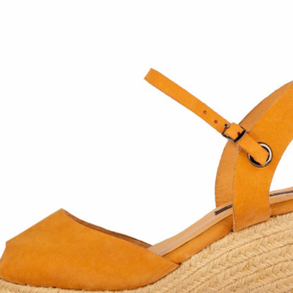 A close up of a handcrafted leather ochre wedge espadrille sandal with jute sole by Miriam Bella on a white background.