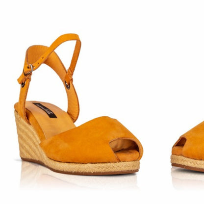Close up of a pair of handcrafted leather ochre wedge espadrille sandals with jute sole by Miriam Bella on a white background.