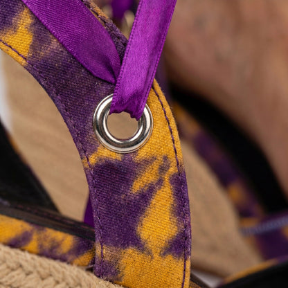Close-up of a Gaia Royal Ember espadrille wedge sandals with a purple ribbon on a blurred background
