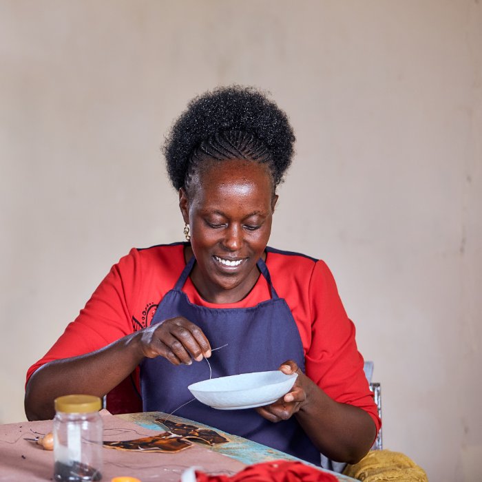 Woman in a red shirt and blue apron preparing food in a kitchen.