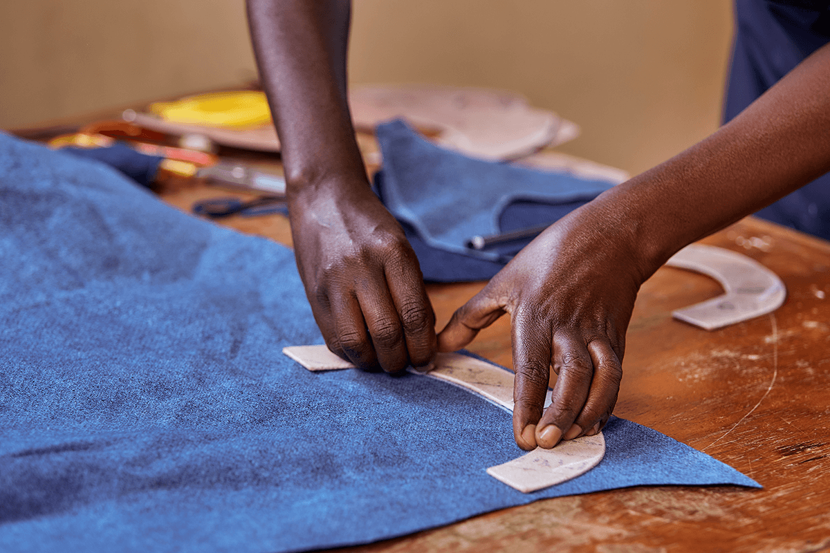 Close-up of artisan hands cutting leather patterns for Miriam Bella handmade shoes in Kenya.