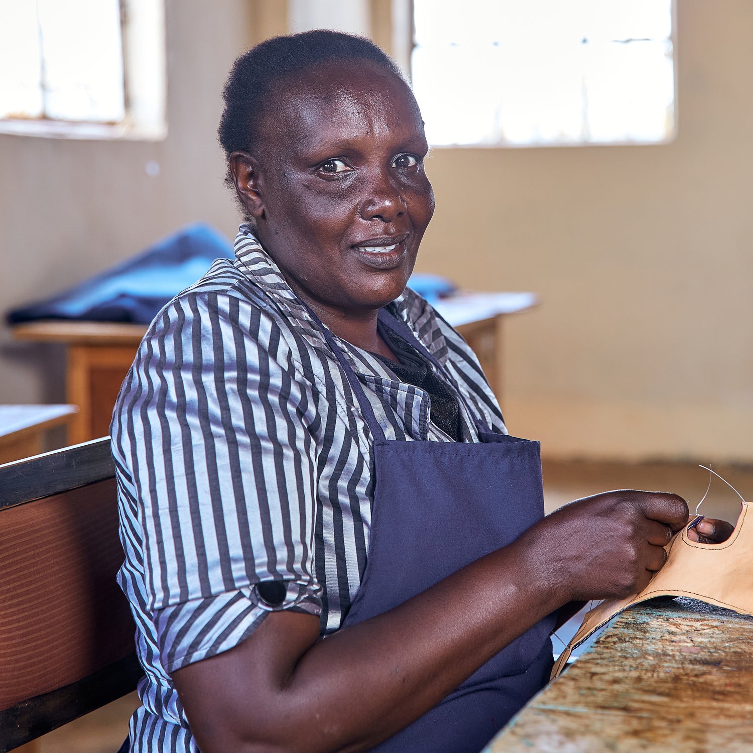 Jepchumba, a Kenya artisan at Miriam Bella, helping create handmade leather sandals and shoes.