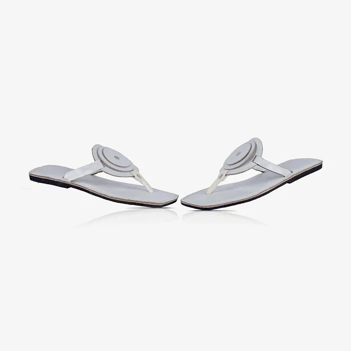 Pair of white women's leather sandals with a unique circle detail and flat design.