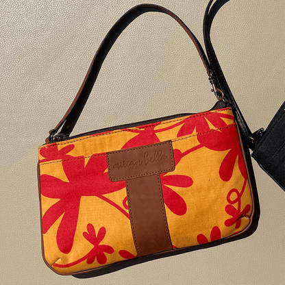 The Floral Mini Tote Bag with red floral pattern and brown strap on a beige background