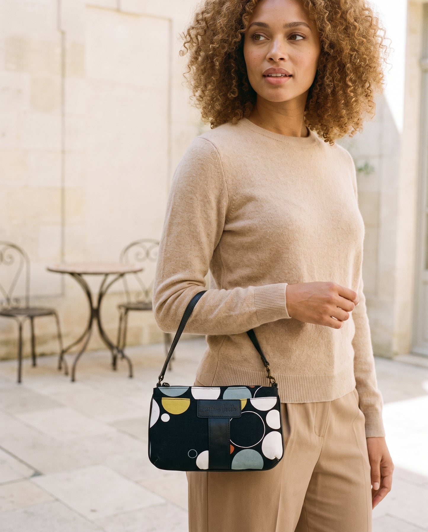 Woman holding the Black Print Mini Tote Bag for Women with circular patterns on her right arm.