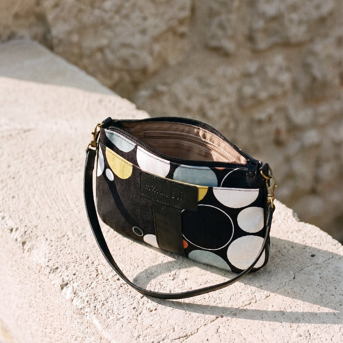Black Print Mini Tote Bag for Women with zipper open on a stone ledge.