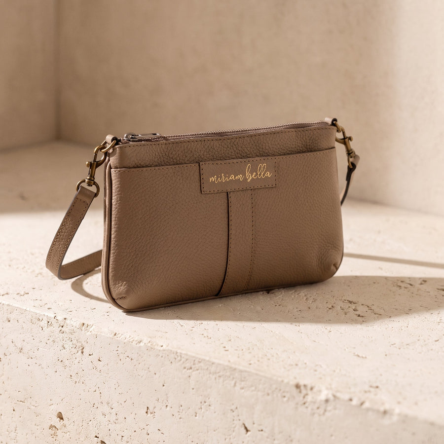 The Mini Tote in moss colour on a stone bench.