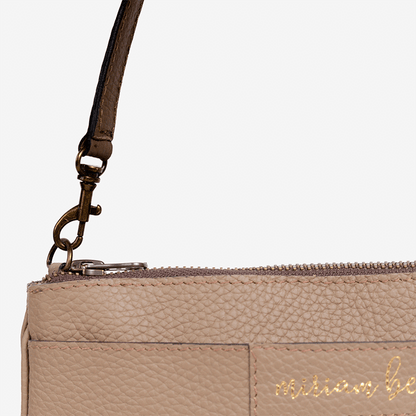 Close-up of the Mini Tote, a beige handbag with a strap and 'Miriam Bella' branding on a light gray background