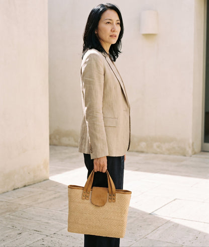 A woman holding a Woven tote bag with leather handles standing outside
