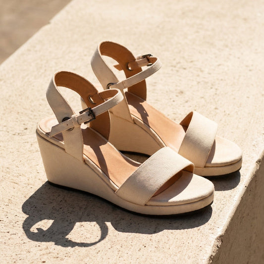 A close up shot of a woman's feet wearing  beighe espadrille wedge sandals standing on a stone terrace outdoor setting
