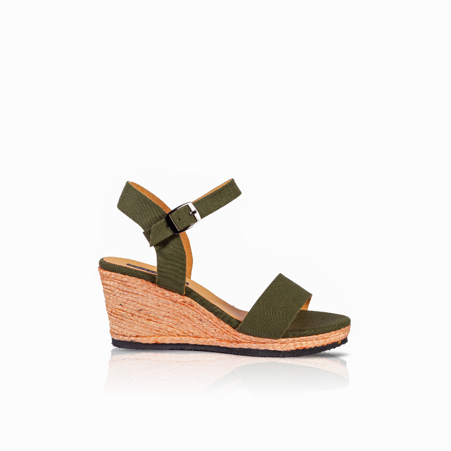 An olive green wedge sandal with a single wide strap, an adjustable ankle strap with a silver buckle, and a textured cork-wrapped wedge heel, shown from a side profile on a white background.