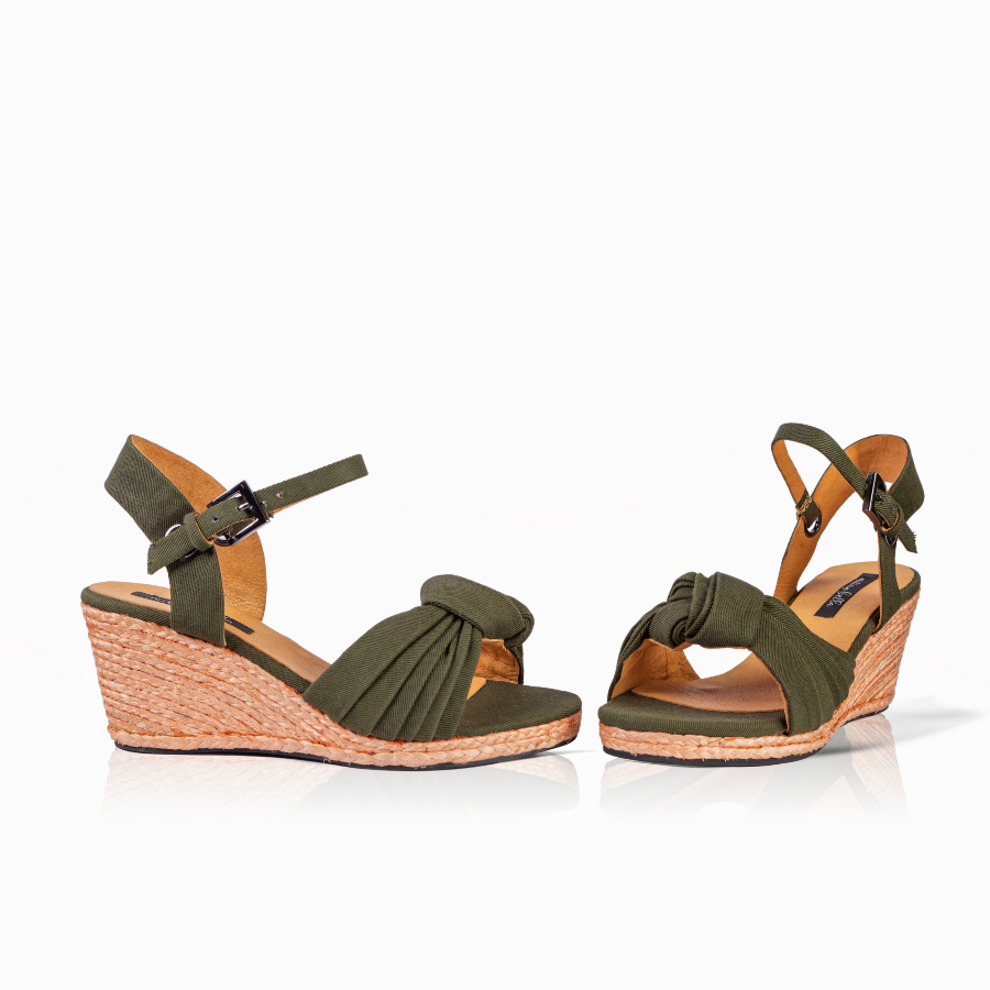 A pair of women's wedge sandals in olive green with a knotted front detail, adjustable ankle straps, and a natural jute-wrapped wedge heel, shown on a white background.