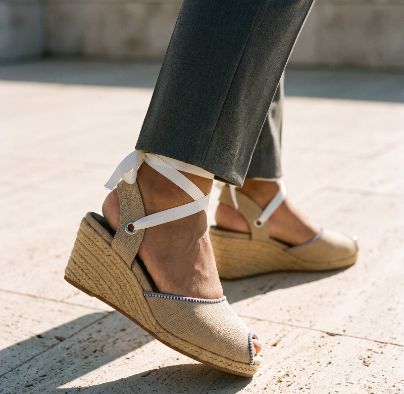 Close-up of Gaia cream canvas peep toe espadrille wedge heels with black ribbon ankle ties.