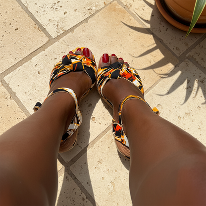 Colorful sandals worn on feet with a neutral background