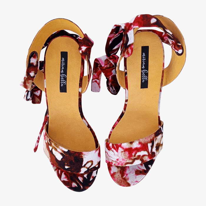 Pair of floral high-heeled shoes with brand label on a white background