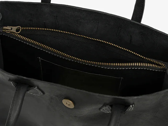 Close-up of a black leather tote bag with a gold zipper.