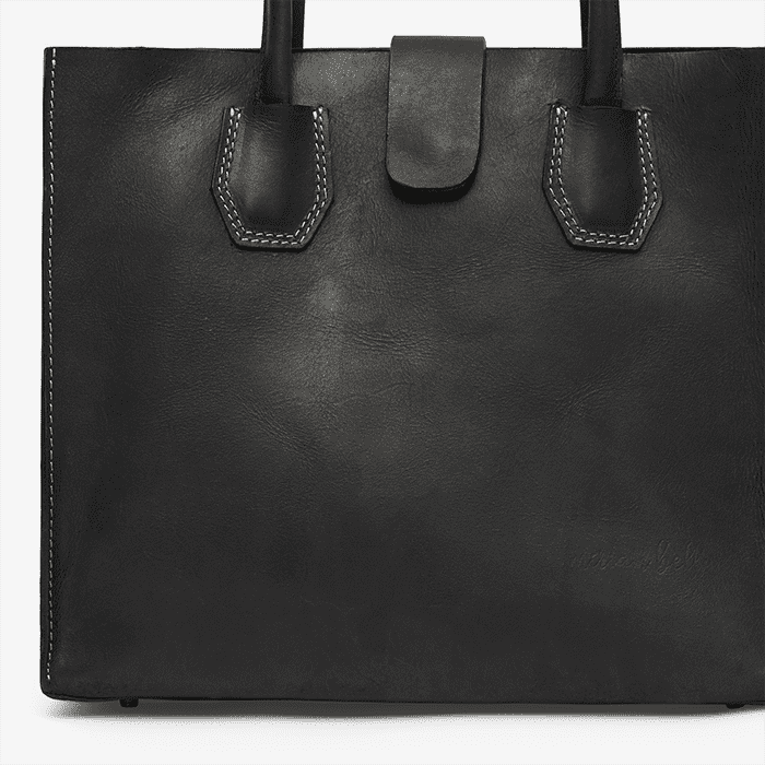 Black leather tote bag with handles on a white background