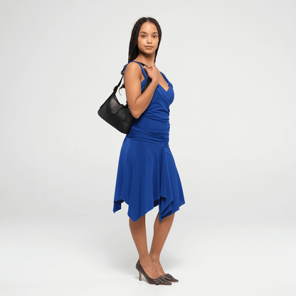 Woman wearing a blue dress with a black leather mini shoulder bag on a white background