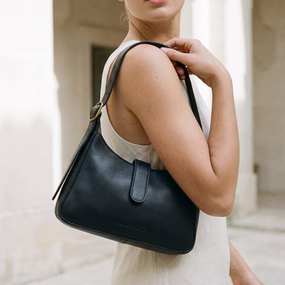 Woman carrying a black leather shoulder bag in an outdoor setting