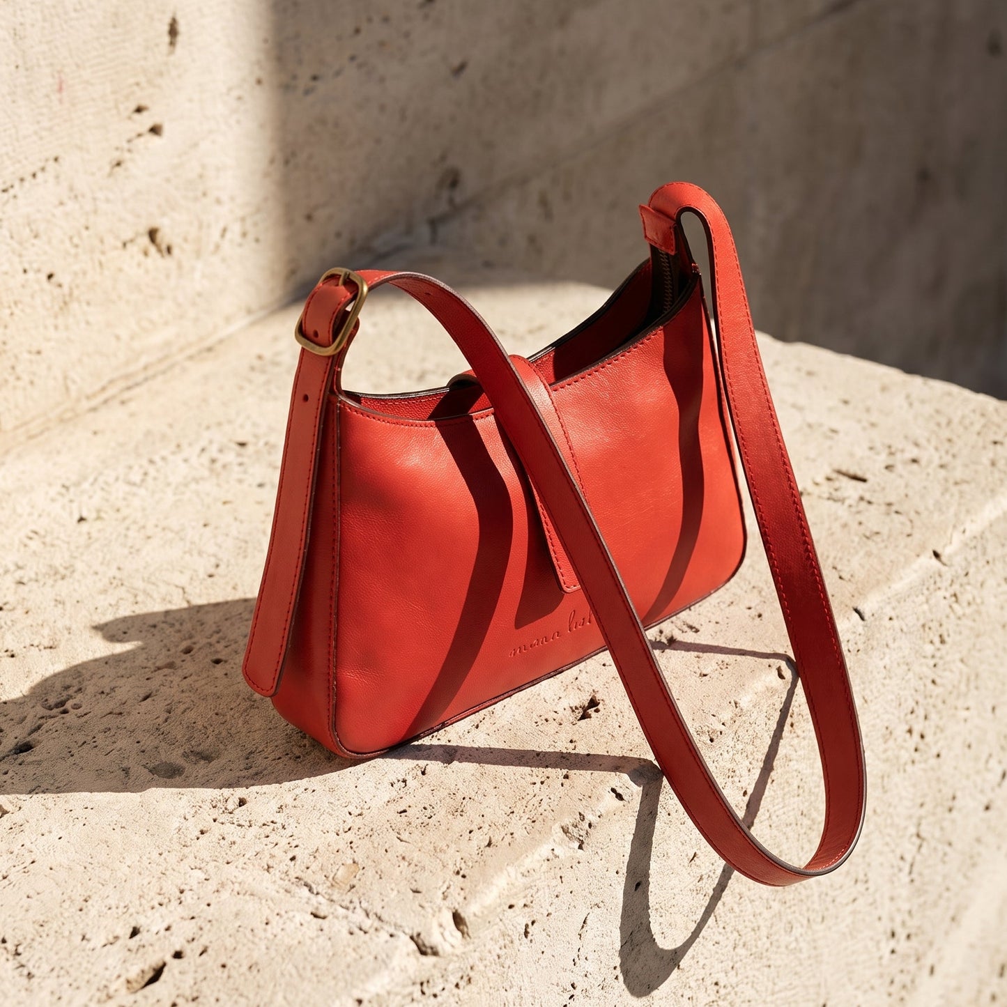 Red leather mini bag on a textured stone surface