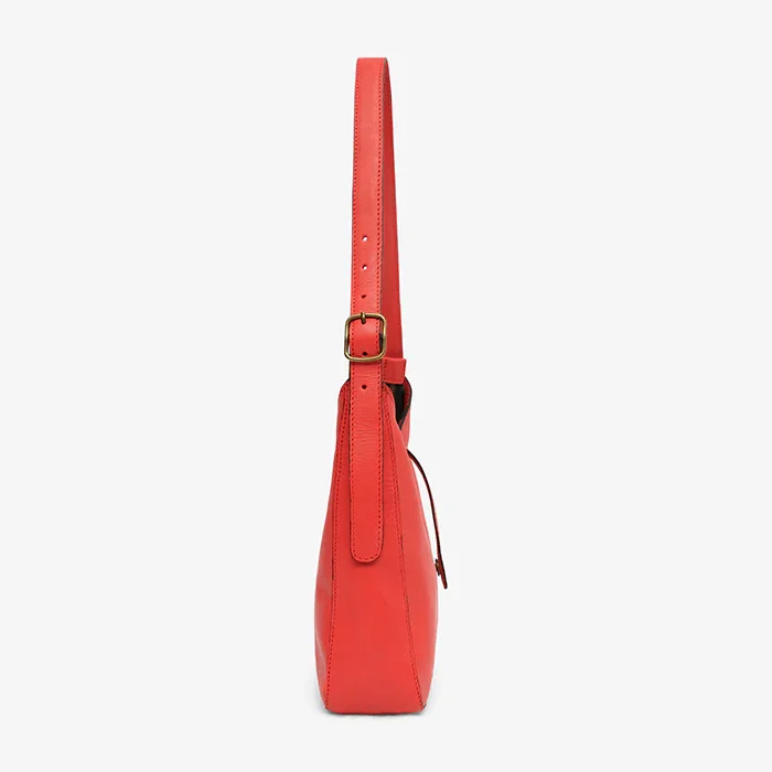 Red leather shoulder bag with a strap on a white background